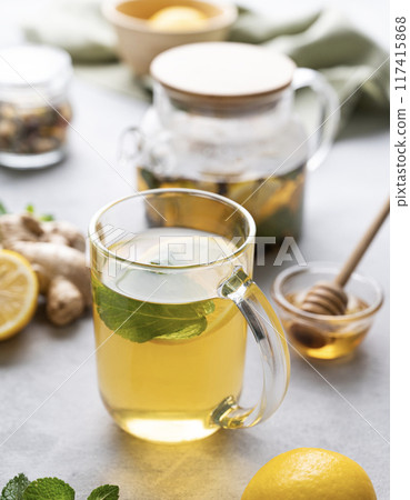 A glass of tea with fresh lemon, honey, mint and ginger on a light background 117415868