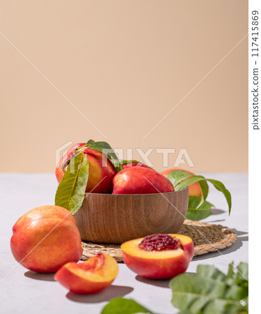 Juicy and sweet nectarines in a bowl on a light background with shadow. Healthy organic farm fruit 117415869