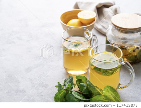 Two glasses of tea with fresh lemon, honey, mint and ginger on a light background Two glasses of tea with fresh lemon, honey, mint and ginger on a light background 117415875