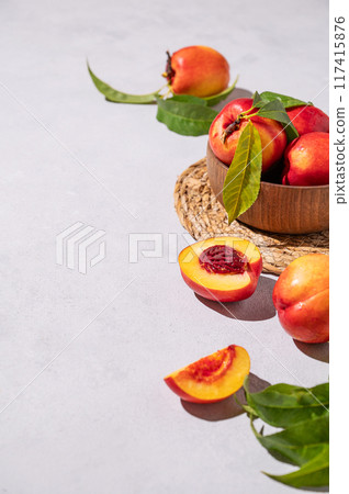 Juicy and sweet nectarines in a bowl on a light background with shadow. Healthy organic farm fruit Juicy and sweet nectarines in a bowl on a light background with shadow. Healthy organic farm fruit 117415876