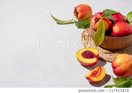 Juicy and sweet nectarines in a bowl on a light background with shadow. Healthy organic farm fruit Juicy and sweet nectarines in a bowl on a light background with shadow. Healthy organic farm fruit 117415878
