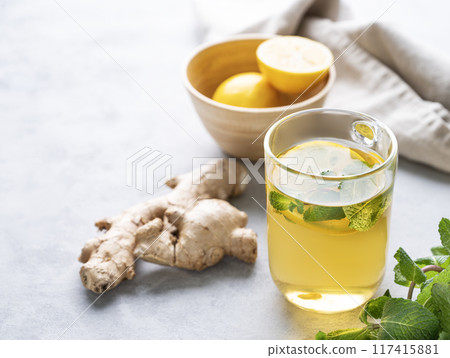 Herbal tea with fresh lemon, mint and ginger on a light background with morning light. Herbal tea with fresh lemon, mint and ginger on a light background with morning light. 117415881