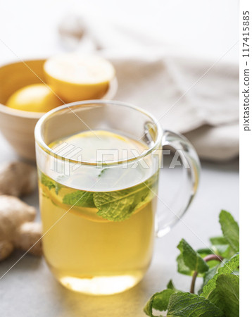 Herbal tea with fresh lemon, mint and ginger on a light background with morning light close up.  117415885