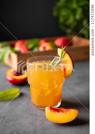 Peach tea with ice and rosemary on a glass. Vegan homemade healthy  drink on a dark background 117415896