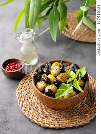 A set of green and black dried olives in bowl on a dark background with olive oil and eucalyptus A set of green and black dried olives in bowl on a dark background with olive oil and eucalyptus 117416121