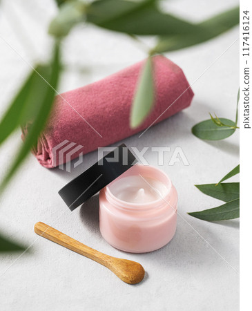 Face and body cream on a light background close up. The concept of care cosmetics with eucalyptus. Face and body cream on a light background close up. The concept of care cosmetics with eucalyptus. 117416124