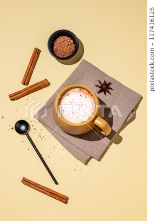 Flat lay of a yellow cup on a napkin with foamy drink coffee latte, hot chocolate or cocoa Flat lay of a yellow cup on a napkin with foamy drink coffee latte, hot chocolate or cocoa 117416126