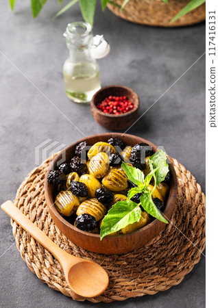 A set of green and black dried olives in bowl on a dark background with olive oil and red pepper 117416131