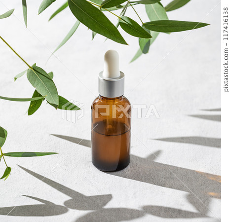 Face and body serum on a light background with shadow. The concept of rose water care cosmetics Face and body serum on a light background with shadow. The concept of rose water care cosmetics 117416138