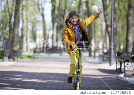 Happy boy on a scooter in the park. 117416296