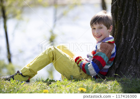 The child is sitting on the grass. Happy boy on a walk in the park. The child is sitting on the grass. Happy boy on a walk in the park. 117416300
