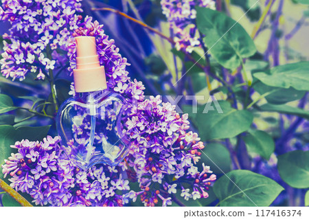 Pink atomizer spray among delicate purple lilac flowers 117416374