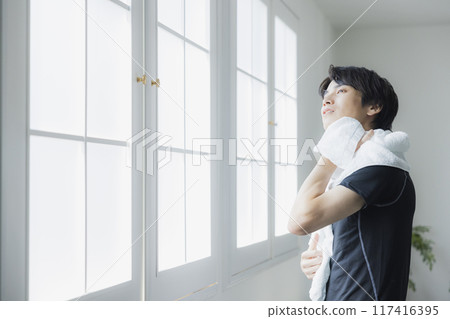 Young man in sportswear wiping sweat with a towel 117416395