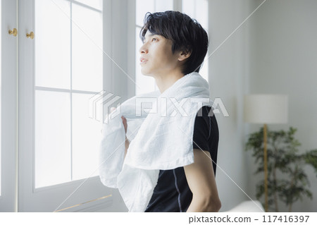 Young man in sportswear wiping sweat with a towel Young man in sportswear wiping sweat with a towel 117416397