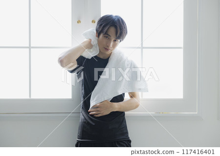Young man in sportswear wiping sweat with a towel Young man in sportswear wiping sweat with a towel 117416401