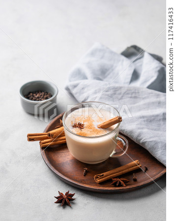 Traditional Indian masala chai latte in a glass cup. Hot drink with milk, spices and herbs  117416433