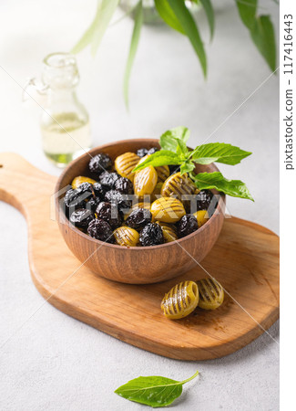 A set of green and black dried olives in wooden  bowl on a light background with olive oil and basil 117416443