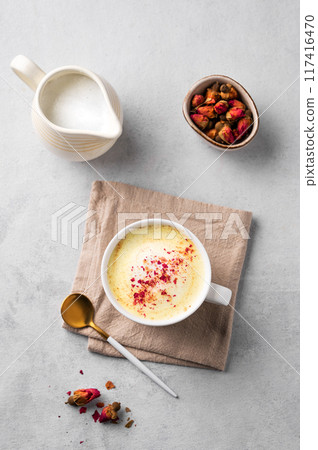 Flat lay of a golden milk latte with turmeric and rose petals. Trendy Indian drink Moon milk  117416470