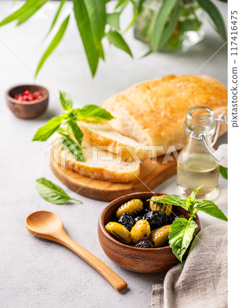 A set of green and black dried olives in wooden bowl with fresh chiabatta bread A set of green and black dried olives in wooden bowl with fresh chiabatta bread 117416475