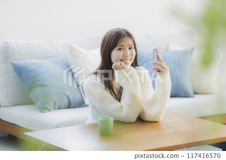 A young woman in knitwear relaxing in a room 117416570