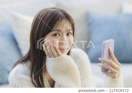 A young woman in knitwear relaxing in a room 117416572