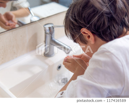 A boy washing his face under running tap A boy washing his face under running tap 117416589