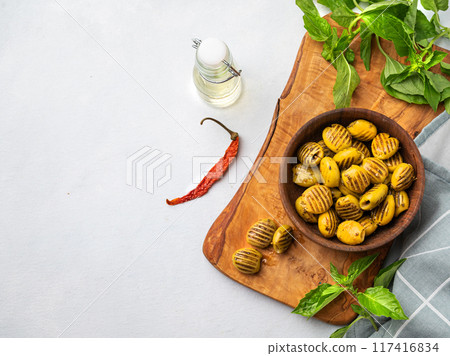 A green grill olives in wooden  bowl on a light background with olive oil and basil.  117416834
