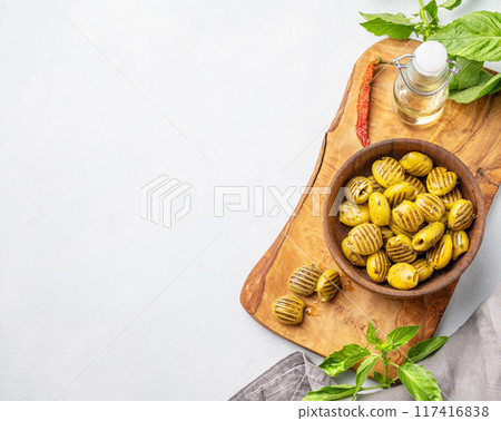 A green grill olives in wooden bowl on a light background with olive oil and basil. A green grill olives in wooden bowl on a light background with olive oil and basil. 117416838