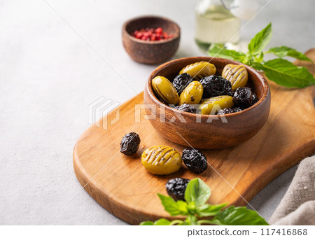 A set of green and black dried olives in bowl on a light background with olive oil and basil A set of green and black dried olives in bowl on a light background with olive oil and basil 117416868