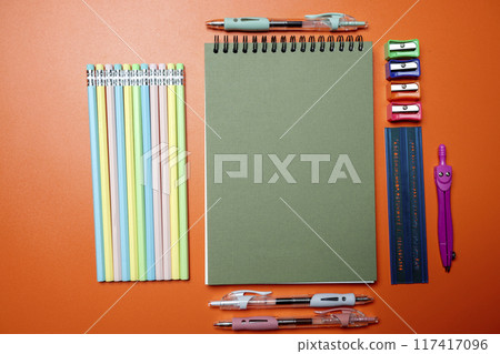 A green notebook sits on a table with a variety of writing utensils A green notebook sits on a table with a variety of writing utensils 117417096