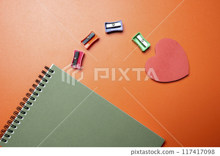 A notebook with a red heart on it and a pencil sharpener on top of it 117417098