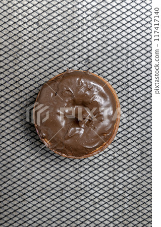 A chocolate mini donut sits on a metal mesh A chocolate mini donut sits on a metal mesh 117417140