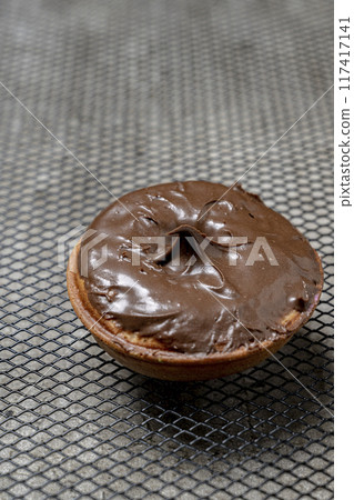 A chocolate mini donut sits on a metal mesh 117417141