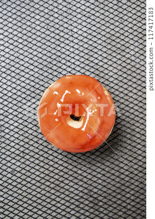 A mini donut with a red glaze sits on a black surface A mini donut with a red glaze sits on a black surface 117417183