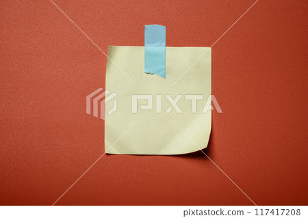 A yellow and blue sticky note is stuck to a red background A yellow and blue sticky note is stuck to a red background 117417208