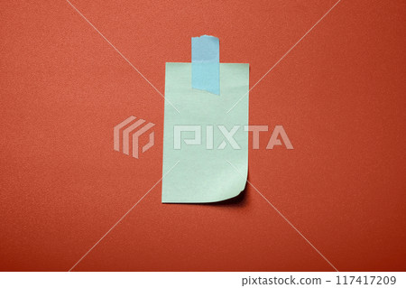 A blue sticky note is stuck to a red wall 117417209