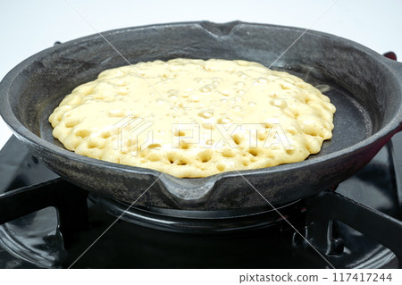 A pan of batter is cooking on a stove A pan of batter is cooking on a stove 117417244