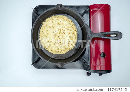 A pan of batter is cooking on a stove A pan of batter is cooking on a stove 117417245