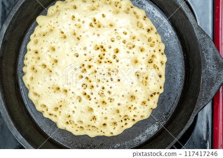 A pan of batter is cooking on a stove 117417246