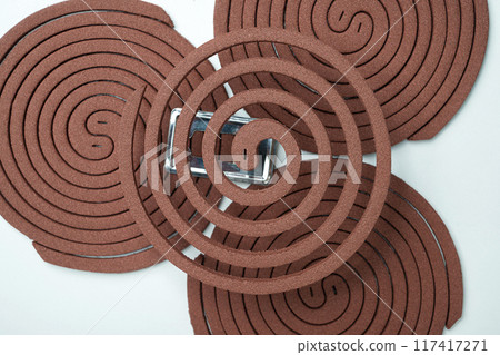 Mosquito coils with a spiral shape is surrounded by other brown objects 117417271