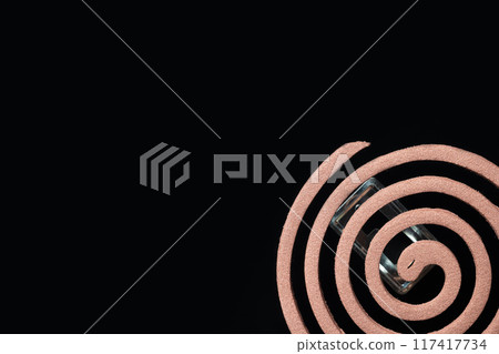 A spiral of mosquito coils is on a black background 117417734