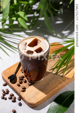 Iced coffee brew in a glass on a wooden board on a light background with coffee beans Iced coffee brew in a glass on a wooden board on a light background with coffee beans 117417965