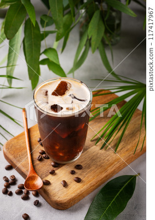 Iced coffee brew in a glass on a wooden board on a light  background with coffee beans 117417967