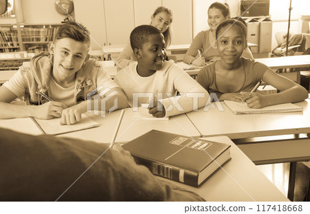 Smiling students sitting at their desks in classroom Smiling students sitting at their desks in classroom 117418668