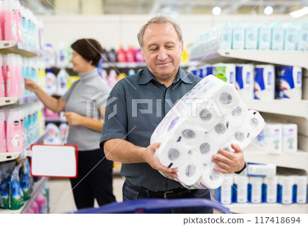 Elderly man chooses toilet paper in supermarket 117418694