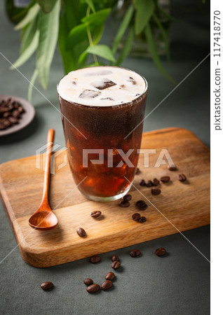 Iced coffee brew in a glass on a wooden board on a green background with coffee beans Iced coffee brew in a glass on a wooden board on a green background with coffee beans 117418770