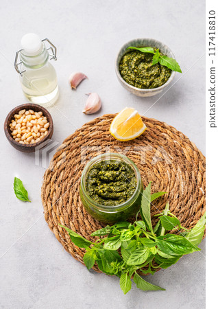 Traditional Italian pesto in a jar with green basil, pine nuts, cheese and olive oil  117418810