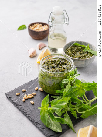 Traditional Italian pesto in a jar with green basil, pine nuts, cheese and olive oil Traditional Italian pesto in a jar with green basil, pine nuts, cheese and olive oil 117418812