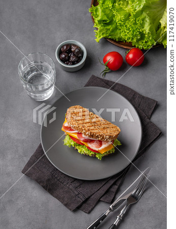 Club sandwich on a plate with a bacon, cheese, tomato and lettuce on a dark background 117419070