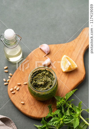 Traditional Italian pesto in a jar with green basil, pine nuts, cheese and olive oil  117419089